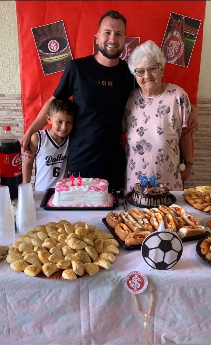 Moradora, Renan e seu filho posando junto à mesa da comemoração