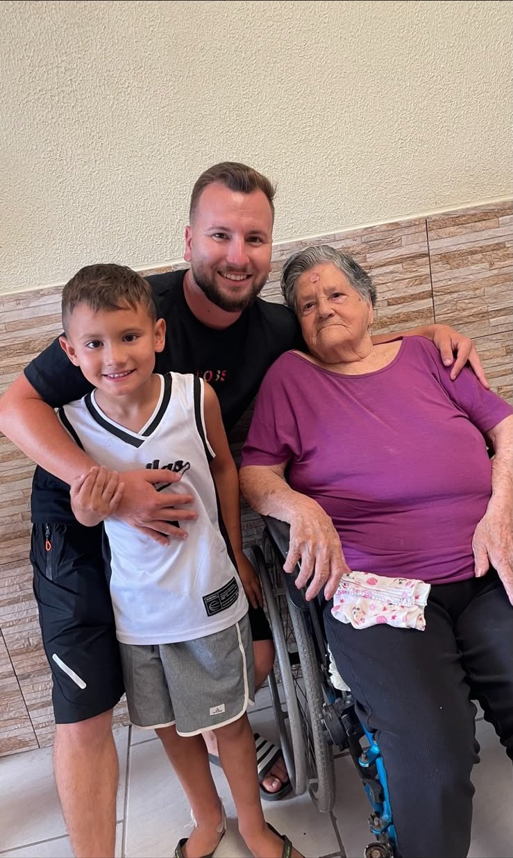 Renan e o filho ao lado de uma moradora em cadeira de rodas
