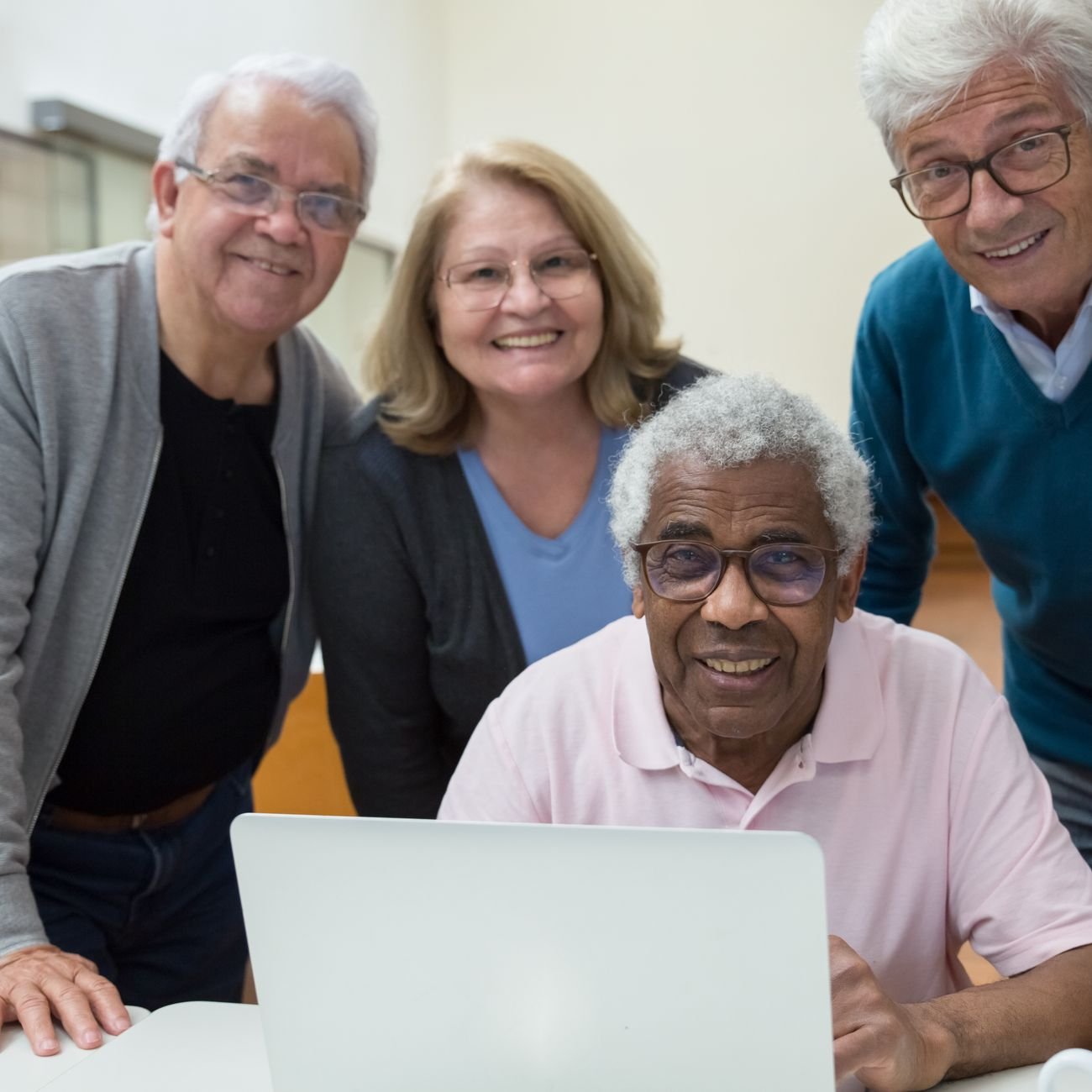 Grupo de idosos de diferentes etnias reunidos e sorrindo em atividade no lar